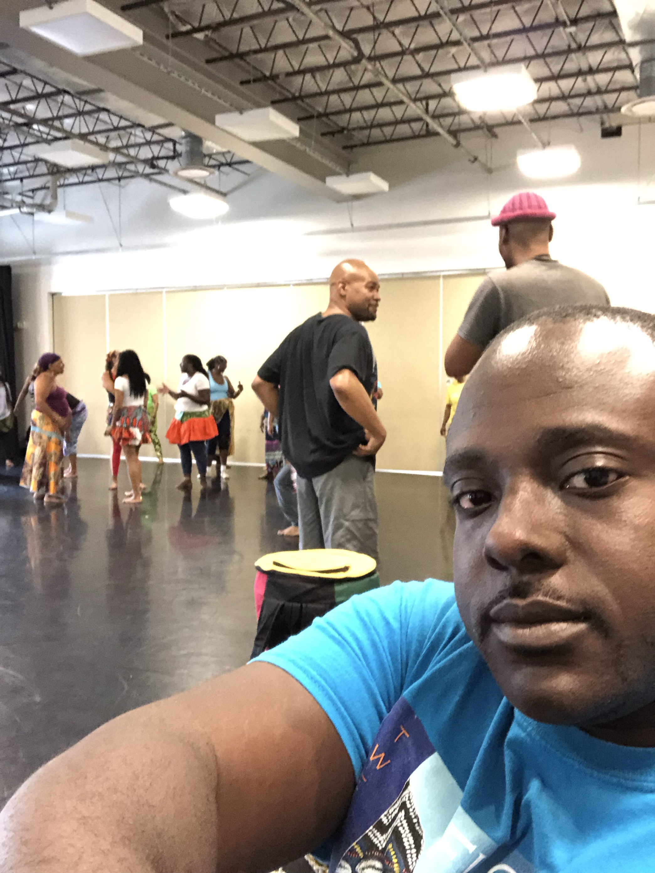 Baba Eddie in a dance studio with dancers and drummers rehearsing in the background
