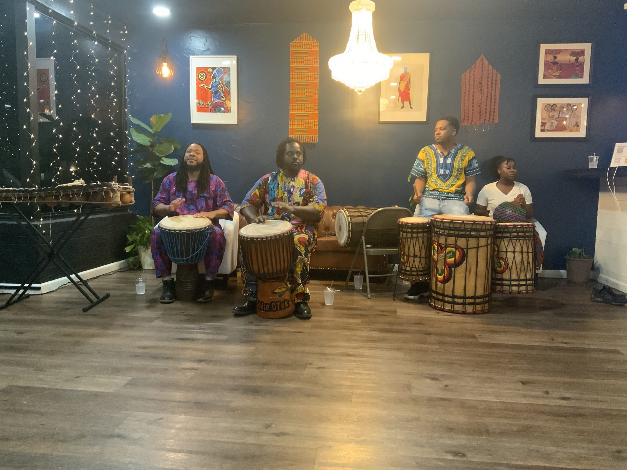 A four-piece ensemble of djembe, dunun and balafon players performing in an intimate blue-walled venue